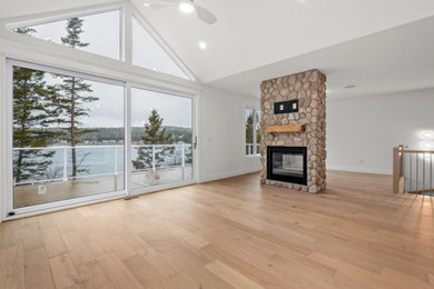Inspiration for a mid-sized coastal open concept light wood floor, beige floor and vaulted ceiling living room remodel in Other with white walls, a two-sided fireplace and a stone fireplace