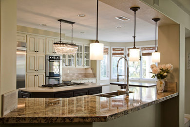 Large trendy u-shaped kitchen photo in Orange County with glass-front cabinets, white cabinets, granite countertops, beige backsplash, porcelain backsplash, stainless steel appliances and an island