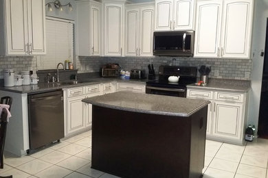 Inspiration for a mid-sized contemporary l-shaped eat-in kitchen in Orlando with an undermount sink, white cabinets, black appliances, with island, raised-panel cabinets, granite benchtops, grey splashback and ceramic floors.
