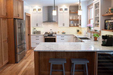 Transitional u-shaped eat-in kitchen in New York with a farmhouse sink, glass-front cabinets, white cabinets, quartzite benchtops, white splashback, porcelain splashback, stainless steel appliances, medium hardwood floors and white benchtop.