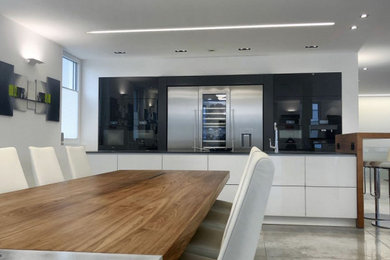 Offene, Zweizeilige, Geräumige Moderne Küche mit integriertem Waschbecken, flächenbündigen Schrankfronten, Edelstahlfronten, Mineralwerkstoff-Arbeitsplatte, Küchengeräten aus Edelstahl, Kücheninsel und schwarzer Arbeitsplatte in Sonstige