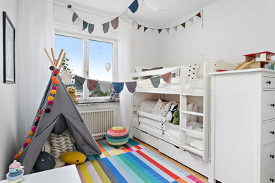 This is an example of a mid-sized scandinavian gender-neutral kids' bedroom for kids 4-10 years old in Stockholm with white walls.