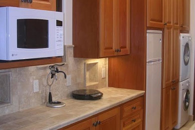 Mid-sized arts and crafts l-shaped eat-in kitchen photo in Other with an undermount sink, shaker cabinets, dark wood cabinets, limestone countertops, beige backsplash, stone tile backsplash, stainless steel appliances and an island