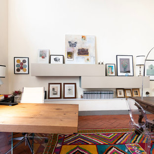 Photo of a large modern study room in Florence with white walls, terra-cotta floors, a standard fireplace, a concrete fireplace surround, a freestanding desk and brown floor.
