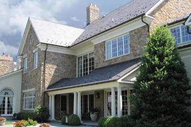 Inspiration for a huge timeless brown three-story stone house exterior remodel in Other with a tile roof and a gray roof