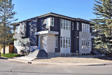Mid-sized trendy gray two-story stucco duplex exterior photo in Calgary with a hip roof and a shingle roof
