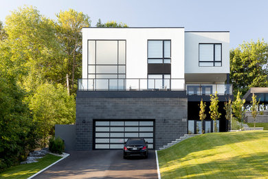 This is an example of a large contemporary two-storey white house exterior in Montreal with mixed siding and a flat roof.