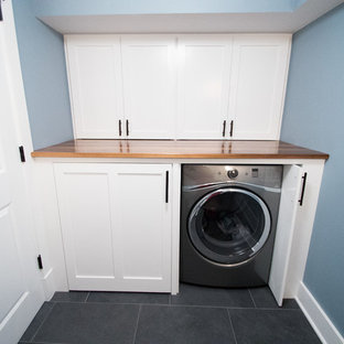 ニューヨークの中サイズのトランジショナルスタイルのおしゃれな洗濯室 (青い壁、シェーカースタイル扉のキャビネット、白いキャビネット、木材カウンター、スレートの床、左右配置の洗濯機・乾燥機) の写真