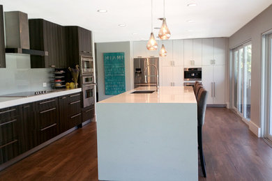 Large minimalist l-shaped dark wood floor enclosed kitchen photo in Miami with an undermount sink, flat-panel cabinets, stainless steel appliances, an island, white cabinets, solid surface countertops, white backsplash and glass tile backsplash