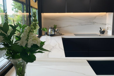 Inspiration for a small contemporary u-shaped separate kitchen in Auckland with a single-bowl sink, beaded inset cabinets, black cabinets, quartz benchtops, multi-coloured splashback, engineered quartz splashback, black appliances, dark hardwood floors, no island, brown floor, multi-coloured benchtop and timber.