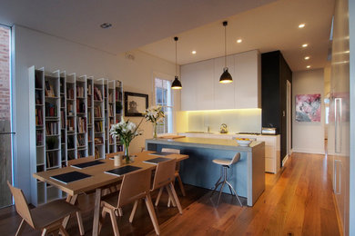 Photo of a small contemporary single-wall eat-in kitchen in Sydney with an undermount sink, flat-panel cabinets, white cabinets, concrete benchtops, white splashback, glass sheet splashback, stainless steel appliances, light hardwood floors and with island.