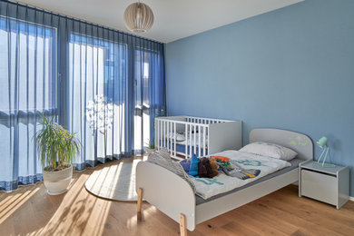 Foto de habitación de bebé niño contemporánea con paredes azules y suelo de madera en tonos medios