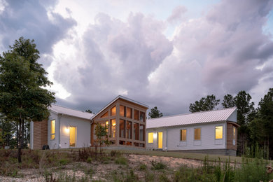 Trendy white concrete fiberboard house exterior photo in Other with a shed roof, a metal roof and a gray roof