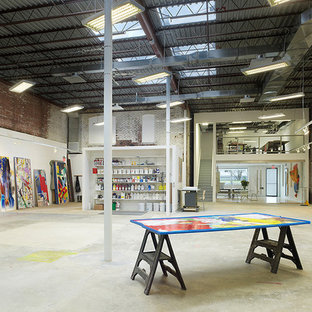 Design ideas for a large industrial home studio in Charlotte with white walls and light hardwood floors.