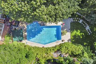 Diseño de piscina grande en patio trasero con paisajismo de piscina y suelo de baldosas