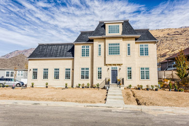 Large elegant beige two-story stucco house exterior photo in Salt Lake City with a shingle roof