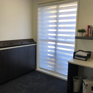 Photo of a medium sized modern study in Sunshine Coast with white walls, carpet, a built-in desk and black floors.