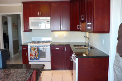 Elegant u-shaped eat-in kitchen photo in Other with an undermount sink, shaker cabinets, red cabinets, granite countertops, white appliances and an island