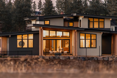 Example of a huge trendy beige two-story stucco exterior home design in Portland with a mixed material roof and a black roof