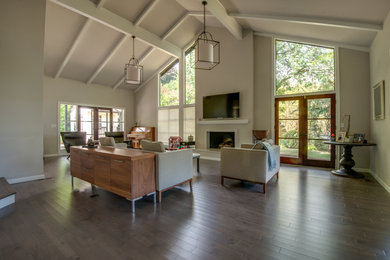 Example of a large classic loft-style light wood floor living room design in Seattle with beige walls, a wall-mounted tv and a standard fireplace