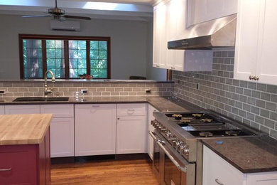 This is an example of a mid-sized modern u-shaped eat-in kitchen in New York with shaker cabinets, white cabinets, soapstone benchtops, multi-coloured splashback, mosaic tile splashback, stainless steel appliances, with island, an undermount sink, medium hardwood floors and brown floor.