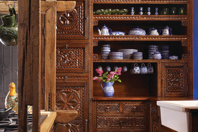 Example of a southwest kitchen design in Albuquerque with a farmhouse sink, distressed cabinets and an island