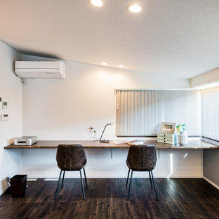他の地域のモダンスタイルのおしゃれなホームオフィス・仕事部屋 (白い壁、塗装フローリング、造り付け机、茶色い床) の写真