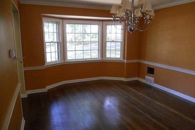 Example of an enclosed dark wood floor living room design in New York with orange walls