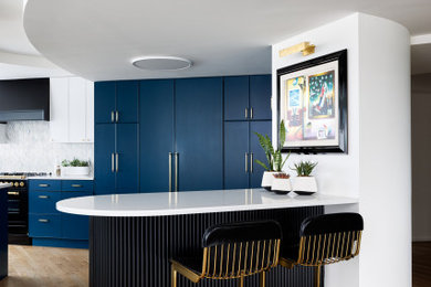 Inspiration for a mid-sized modern u-shaped light wood floor and brown floor eat-in kitchen remodel in DC Metro with a drop-in sink, flat-panel cabinets, blue cabinets, quartz countertops, white backsplash, marble backsplash, black appliances, an island and white countertops