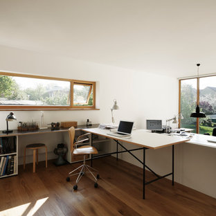 Design ideas for a large modern study in Other with white walls, medium hardwood flooring, a built-in desk and no fireplace.