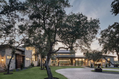 Huge transitional gray two-story stone and board and batten house exterior photo in Austin with a shed roof, a metal roof and a black roof