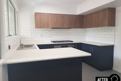 Mid-sized modern u-shaped open plan kitchen in Brisbane with a double-bowl sink, flat-panel cabinets, grey cabinets, laminate benchtops, white splashback, ceramic splashback, stainless steel appliances, vinyl floors, a peninsula, grey floor and white benchtop.