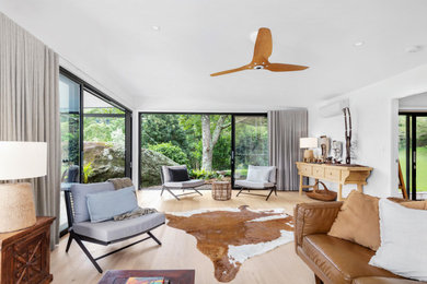 Photo of a mid-sized contemporary open concept living room in Wollongong with white walls and light hardwood floors.