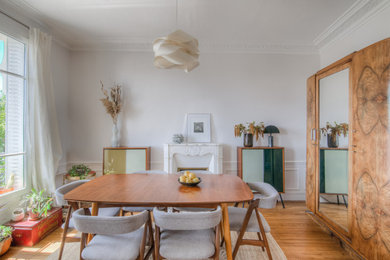 Exemple d'une salle à manger ouverte sur le salon tendance de taille moyenne avec un mur blanc, parquet clair et un sol marron.