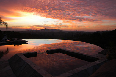 Pool - large contemporary backyard stone and custom-shaped infinity pool idea in San Diego