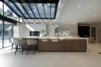 Large modern kitchen in Kent with shaker cabinets, light wood cabinets, quartz worktops, brown splashback, black appliances, an island, brown worktops and a feature wall.