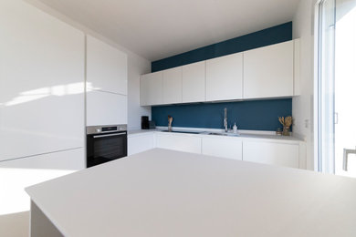 Foto di una cucina moderna di medie dimensioni con lavello sottopiano, top in quarzo composito, paraspruzzi blu, elettrodomestici in acciaio inossidabile, pavimento in laminato, pavimento marrone e top bianco