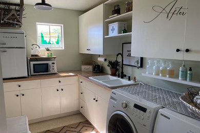 Utility room - country single-wall laminate floor and beige floor utility room idea with a double-bowl sink, flat-panel cabinets, white cabinets, solid surface countertops, white walls, a side-by-side washer/dryer and brown countertops
