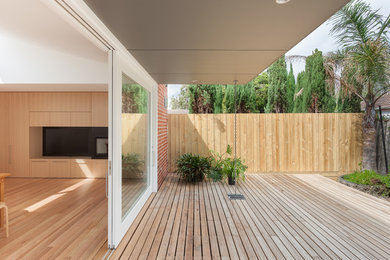 Contemporary backyard deck in Melbourne with a roof extension.