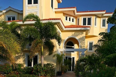 Tropical yellow three-story exterior home idea in Tampa