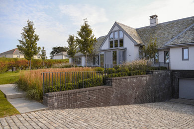 Diseño de fachada de casa blanca y gris costera de tamaño medio de dos plantas con tejado a dos aguas y tejado de teja de barro