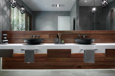 Photo of a large contemporary master bathroom in Melbourne with a vessel sink, flat-panel cabinets, medium wood cabinets, gray tile, porcelain tile, grey walls, porcelain floors, engineered quartz benchtops, grey floor and white benchtops.