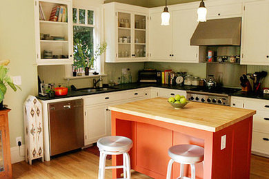 Inspiration for a mid-sized contemporary l-shaped medium tone wood floor kitchen remodel in San Francisco with flat-panel cabinets, white cabinets, wood countertops, stainless steel appliances and an island