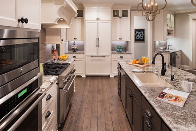 Example of a large classic l-shaped dark wood floor and brown floor open concept kitchen design in Minneapolis with an island, an undermount sink, recessed-panel cabinets, white cabinets, granite countertops, brown backsplash and stainless steel appliances
