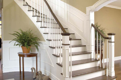 Large elegant wooden curved wood railing staircase photo in Chicago with painted risers