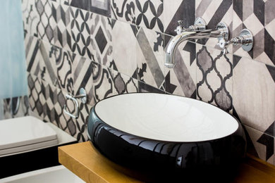 Foto di una stanza da bagno con doccia minimalista con ante nere, piastrelle grigie, piastrelle in ceramica, lavabo a bacinella, top in legno, un lavabo e mobile bagno sospeso
