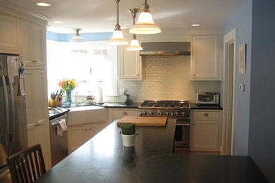 Kitchen - transitional medium tone wood floor kitchen idea in Boston with a farmhouse sink, white cabinets, white backsplash and stainless steel appliances