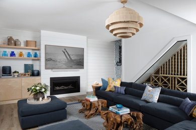 Large beach style walk-out vinyl floor, brown floor and shiplap wall basement photo in New York with a home theater, white walls, a standard fireplace and a shiplap fireplace