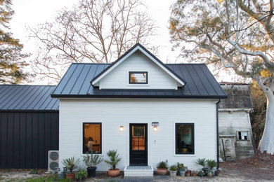 Ejemplo de fachada de casa blanca y negra de estilo de casa de campo de dos plantas con revestimientos combinados, tejado a dos aguas y tejado de metal