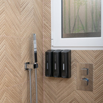 Detalle de ducha con revestimiento efecto madera en espiga y toques contemporáne